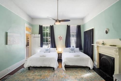two beds in a room with a fireplace at The Mardis Gras Manor Walkable, Historic, Local Treasure in Mobile