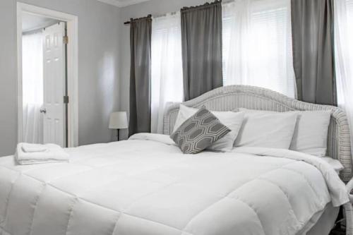 een wit bed met witte kussens in een slaapkamer bij The Graduation Getaway Near Downtown & Benning in Columbus