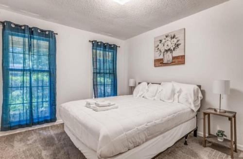 a white bedroom with a large bed with blue curtains at Near Dining Shopping Parks Tranquil Fox Trails in Memphis