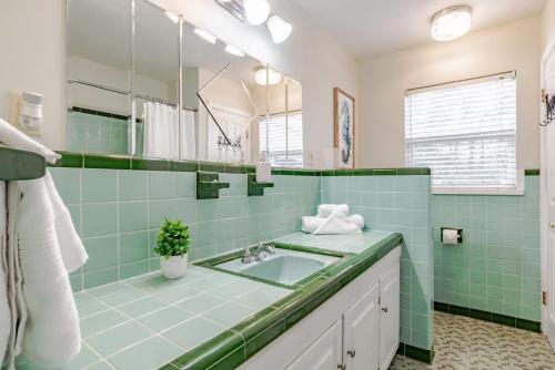 een groene badkamer met een wastafel en een spiegel bij Sunny Side at Dog River-Dock, Lake, Fenced Yard in Mobile