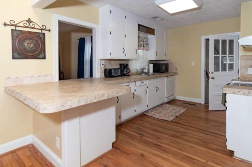 a kitchen with white cabinets and a marble counter top at The Columbus Cottage Mins to Benning Downtown in Columbus