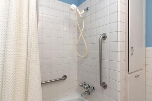 uma casa de banho em azulejos brancos com um chuveiro e um lavatório. em Family-Friendly Near Benning The Crimson Ranch em Columbus