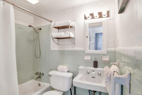 een witte badkamer met een toilet en een wastafel bij Charming Midtown Apt - Hannon Hideaway Unit A in Mobile