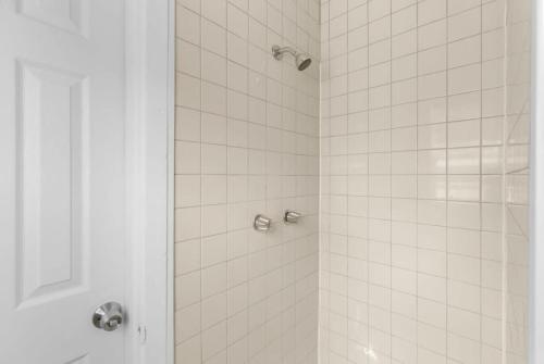 a bathroom with a shower with white tile at 10 Mins to Legion Field Stadium- Blushing Bungalow in Birmingham