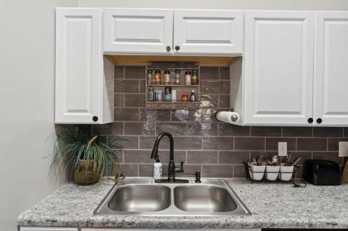 a kitchen counter with a sink and white cabinets at Wistful on Washington-Moon River District in Savannah