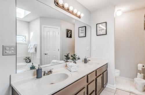 a white bathroom with a sink and a mirror at Fenced Yard - Comfy & Convenient in Cordova in Memphis