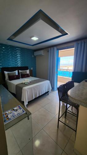 1 dormitorio con cama, mesa y ventana en Flats Bahia, en Coruripe