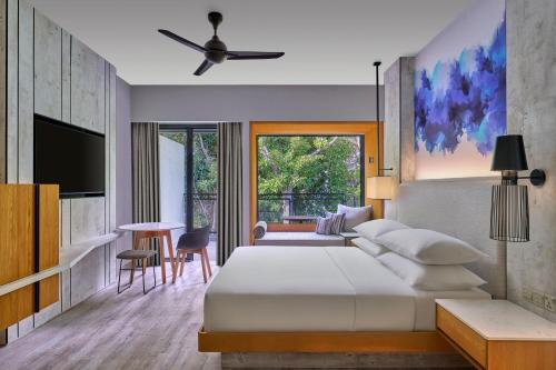 a bedroom with a bed and a tv and a table at Perhentian Marriott Resort & Spa in Perhentian Islands