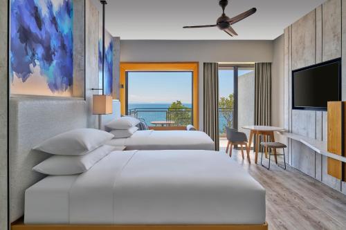 Perhentian Marriott Resort & Spa في بيرهينتيان: غرفة نوم بسريرين وتلفزيون بشاشة مسطحة