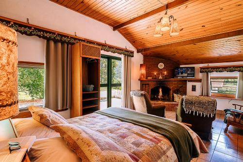 um quarto com uma cama grande e uma lareira em Estalagem Tronador em Camanducaia
