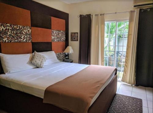 - une chambre avec un grand lit et une fenêtre dans l'établissement Di Villa, à Port Antonio