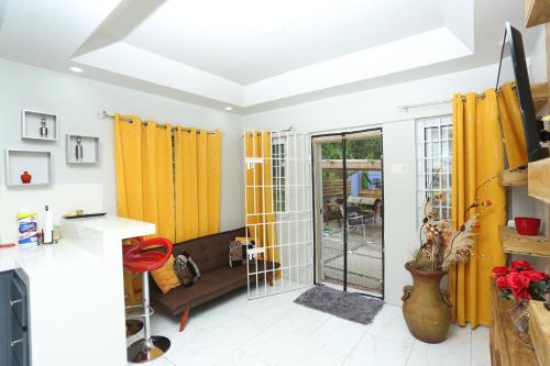 a kitchen with yellow curtains and a living room at Home Away From Home in Kingston