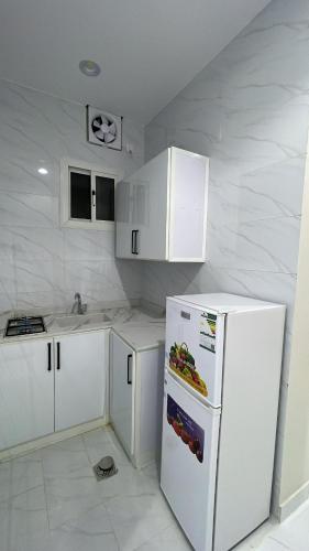 a kitchen with white cabinets and a white refrigerator at منتجع لي فارد in Taif