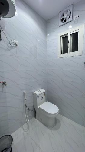 a white bathroom with a toilet and a window at منتجع لي فارد in Taif