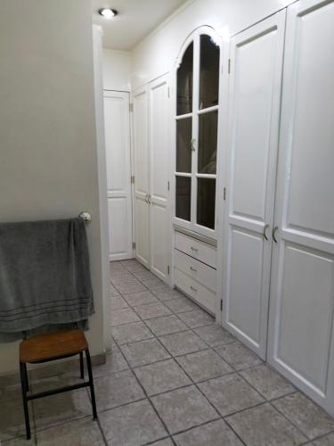 a room with white cabinets and a chair and a tiled floor at Hotel Teui Formarte Grupos in Celaya