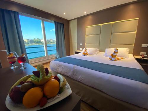Nile Cruise Luxor & Aswoan Included balloon في الأقصر: غرفة نوم مع سرير مع وعاء من الفواكه على طاولة