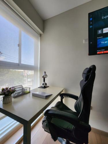 ein Büro mit einem Schreibtisch und einem Stuhl mit einem Computer in der Unterkunft Hab. privada compartida en departamento cerca del aeropuerto in La Libertad