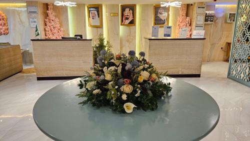 a round table with a bouquet of flowers on it at Rahhal AlBahr Serviced Apartments in Jeddah