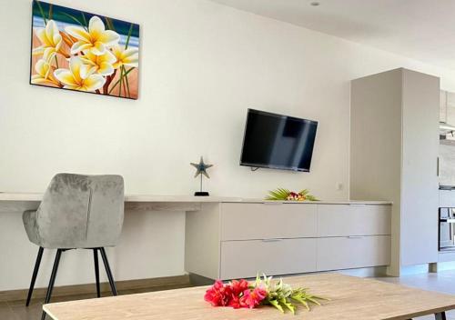 a living room with a desk and a tv on a wall at Mareta Lodge - Studio ONO 6 in Bora Bora