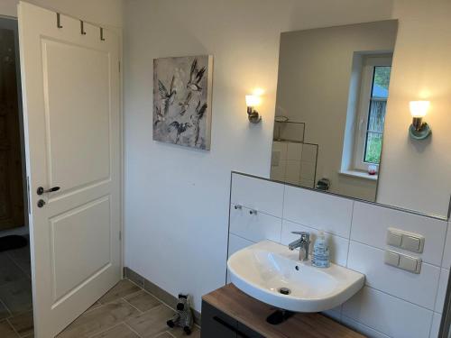 Baño blanco con lavabo y espejo en Landperle 2, en Ulsnis