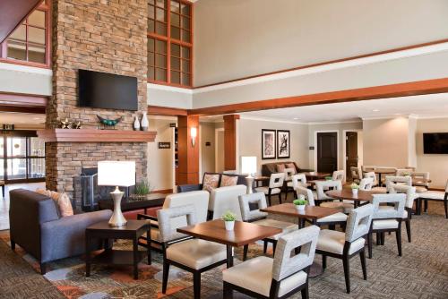 a hotel lobby with tables and chairs and a fireplace at Staybridge Suites - Charlotte Ballantyne, an IHG Hotel in Charlotte