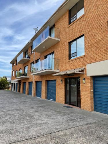 a red brick building with blue garage doors at Woody Wonder Unit 2 South West Rocks in South West Rocks