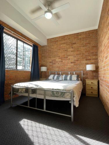 a bedroom with a bed and a brick wall at Woody Wonder Unit 2 South West Rocks in South West Rocks