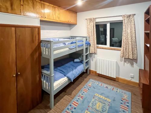 a small room with bunk beds and a window at The Byre in Tayvallich