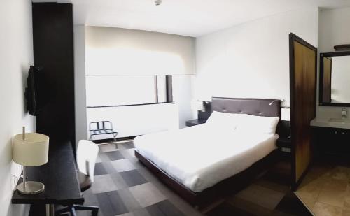 a bedroom with a white bed and a mirror at HOTEL ILAR 120 USAQUEN in Bogotá