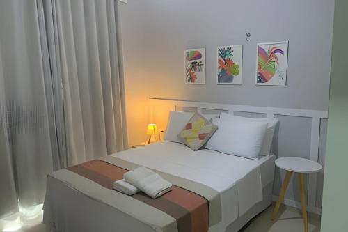 a bedroom with a bed with white sheets and pillows at Hosts BR - La Serena Suíte Cumbuco in Cumbuco