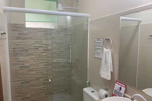 a bathroom with a glass shower with a toilet at Hosts BR - La Serena Suíte Cumbuco in Cumbuco