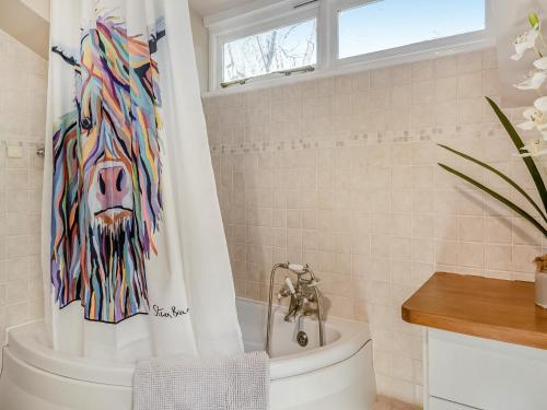 a bathroom with a shower curtain of a lion on the tub at Dunburgh Wood in Beccles