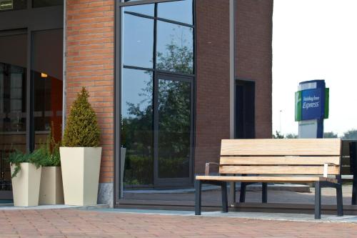 a wooden bench sitting in front of a building at Holiday Inn Express Reggio Emilia by IHG in Reggio Emilia