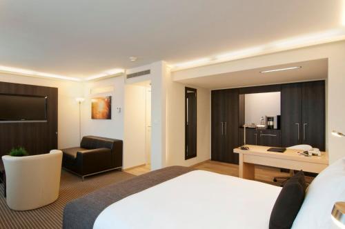 チューリッヒにあるCrowne Plaza Zürich, an IHG Hotelのベッドとデスクが備わるホテルルームです。