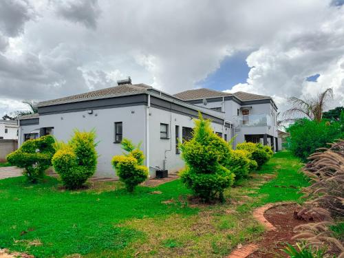 una casa blanca con arbustos delante en holiday villa en Harare