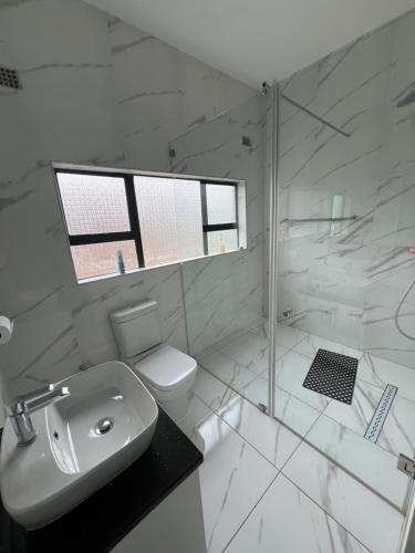 La salle de bains blanche est pourvue d'une douche et de toilettes. dans l'établissement holiday villa, à Harare