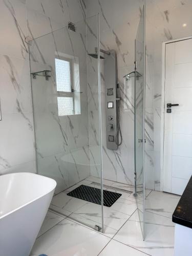 a white bathroom with a shower and a tub at holiday villa in Harare