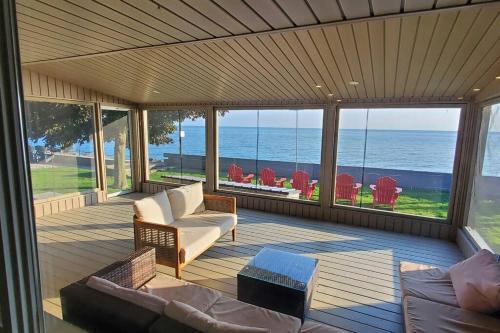 a screened in porch with a view of the ocean at The Driftwood - Hot tub with Lake views in Leamington