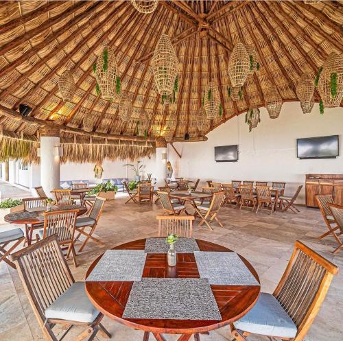 a restaurant with a table and chairs and a straw roof at Departamento de Lujo & Club de Playa in Acapulco