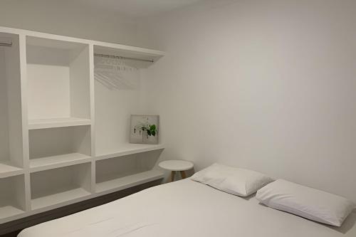 a white bedroom with a bed and shelves at Hosts BR - Apartamentos funcionais in Fortaleza