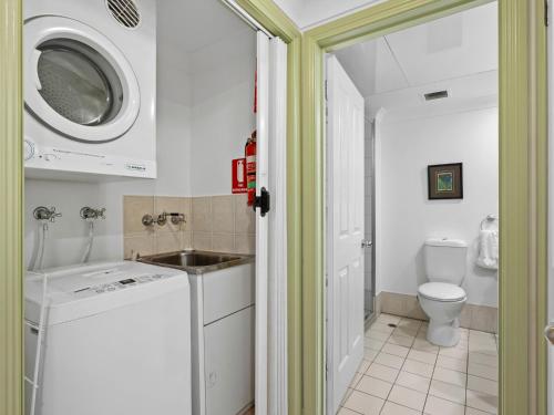 uma casa de banho com uma máquina de lavar e secar roupa e um WC. em Waterfront Terraces em Cairns