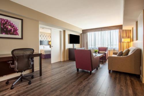 a hotel room with a desk and chairs and a bedroom at Holiday Inn Toronto International Airport by IHG in Toronto