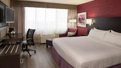 a hotel room with a large bed and a desk at Holiday Inn Toronto International Airport by IHG in Toronto