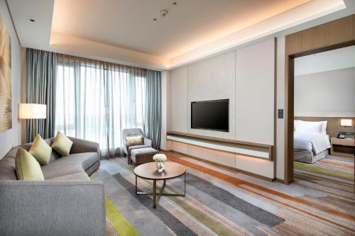 a living room with a couch and a tv and a bed at Holiday Inn Shunde by IHG in Shunde