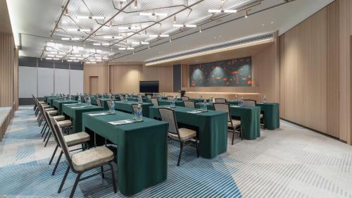 a conference room with green tables and chairs and a screen at EVEN Hotel Zhongshan City Center by IHG in Zhongshan