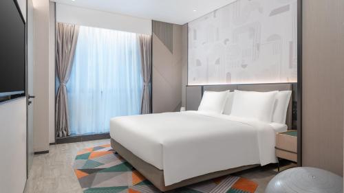 a bedroom with a large white bed and a window at EVEN Hotel Zhongshan City Center by IHG in Zhongshan