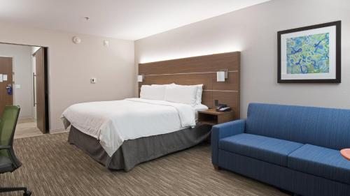 a hotel room with a bed and a blue couch at Holiday Inn Express & Suites Racine, an IHG Hotel in Racine
