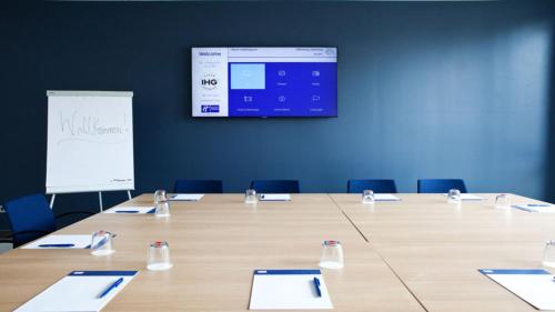 a conference room with a table with chairs and a screen at Holiday Inn Express - Remscheid in Remscheid