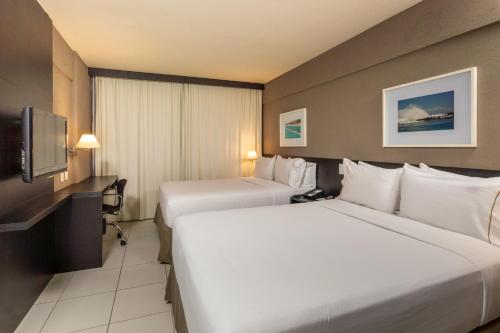 a hotel room with two beds and a tv at Hilton Garden Inn Maceio in Maceió