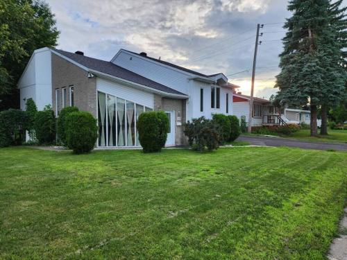 a house with a green lawn in front of it at Timeless Tranquility, a place near everything! in Longueuil